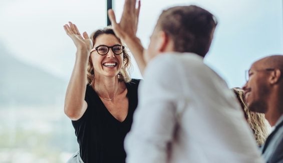 Business professionals high five during a meeting in boardroom